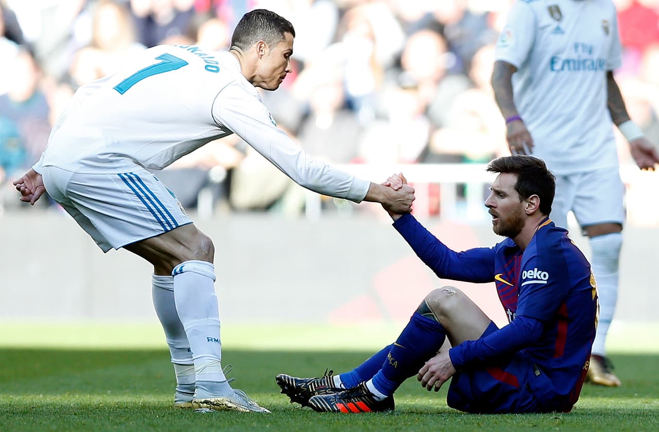 Cristiano Ronaldo, del Real Madrid (izquierda), ayuda a Lionel Messi, del Barcelona, a levantarse durante el partido de la Liga española entre el Real Madrid y el Barcelona en el estadio Santiago Bernabéu de Madrid, España, el sábado 23 de diciembre de 2017.
