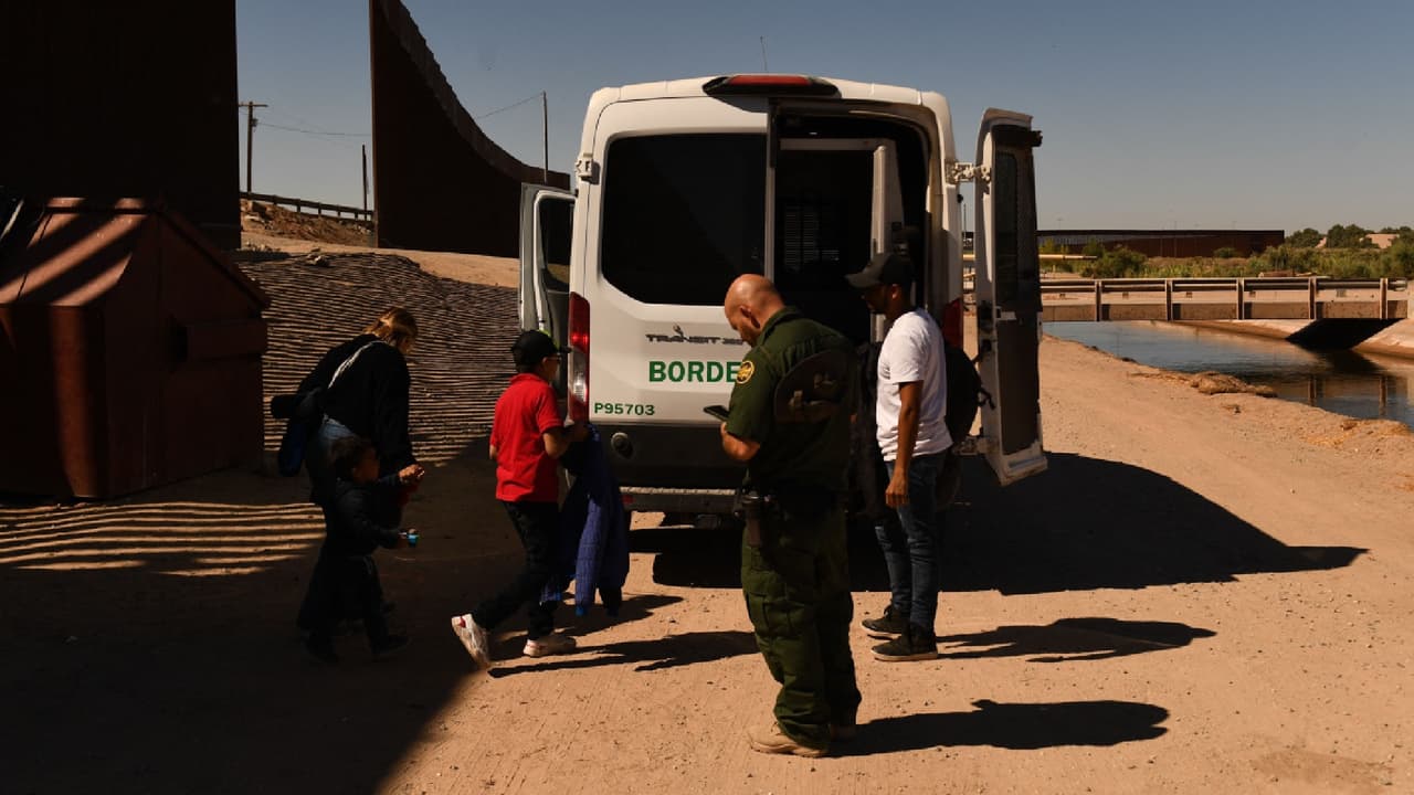 Una familia migrante que busca asilo sube a una camioneta de la Patrulla Fronteriza cuando se presentan después de cruzar a EEUU desde México en un espacio en la represa Morelos a lo largo del muro fronterizo en Yuma, Arizona.