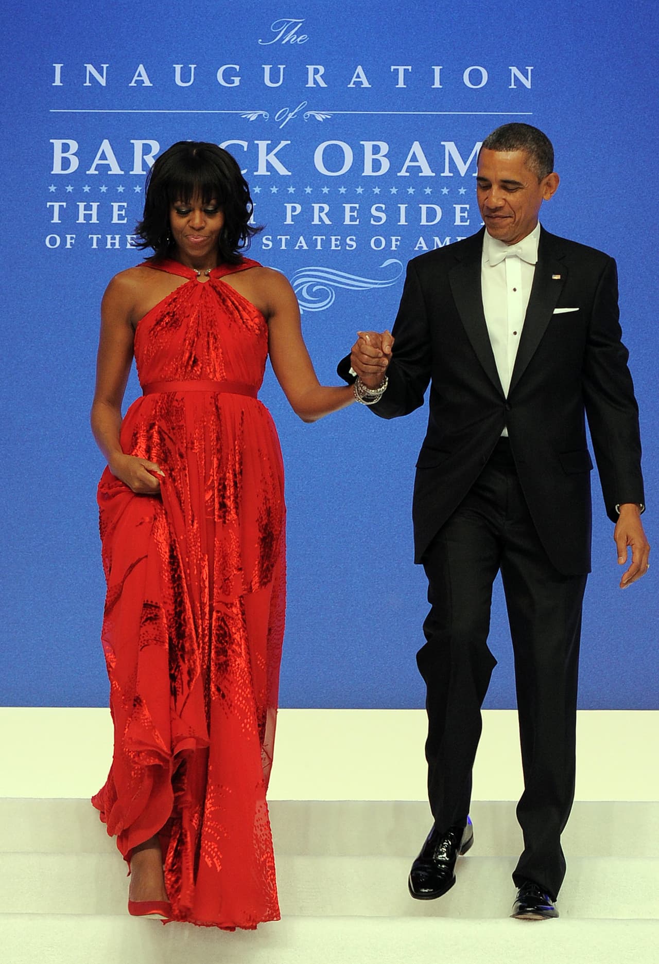 Michelle sabe utilizar un vestido rojo. Sabe que el rojo impacta. Sabe que no hay que recargarlo. Y sabe que puede eclipsar a su marido, pero no del todo.