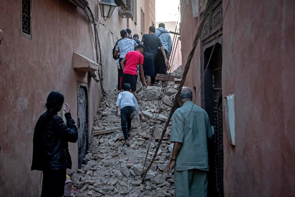 Residentes evacúan la zona caminando sobre calles cubiertas de escombros en la ciudad vieja de Marrakech.