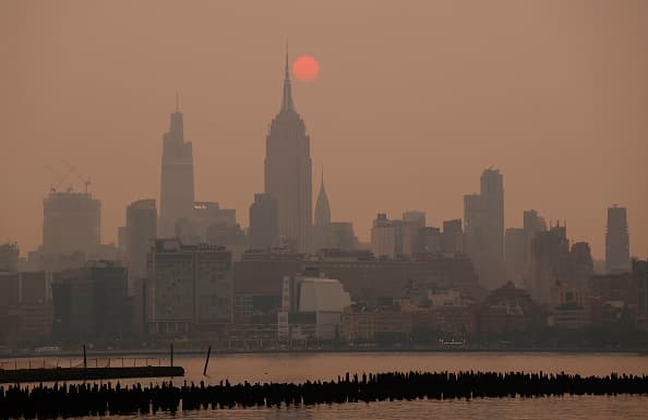 Parece un globo naranja sobre el rascacielos, pero es el sol en un color poco frecuente.