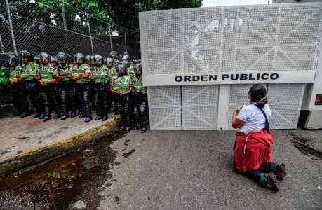 A woman kneels in front of a phalanx of the Bolivarian National Police that blocked an opposition march in Caracas April 22. (Juan Barreto / AFP / GettyImages).