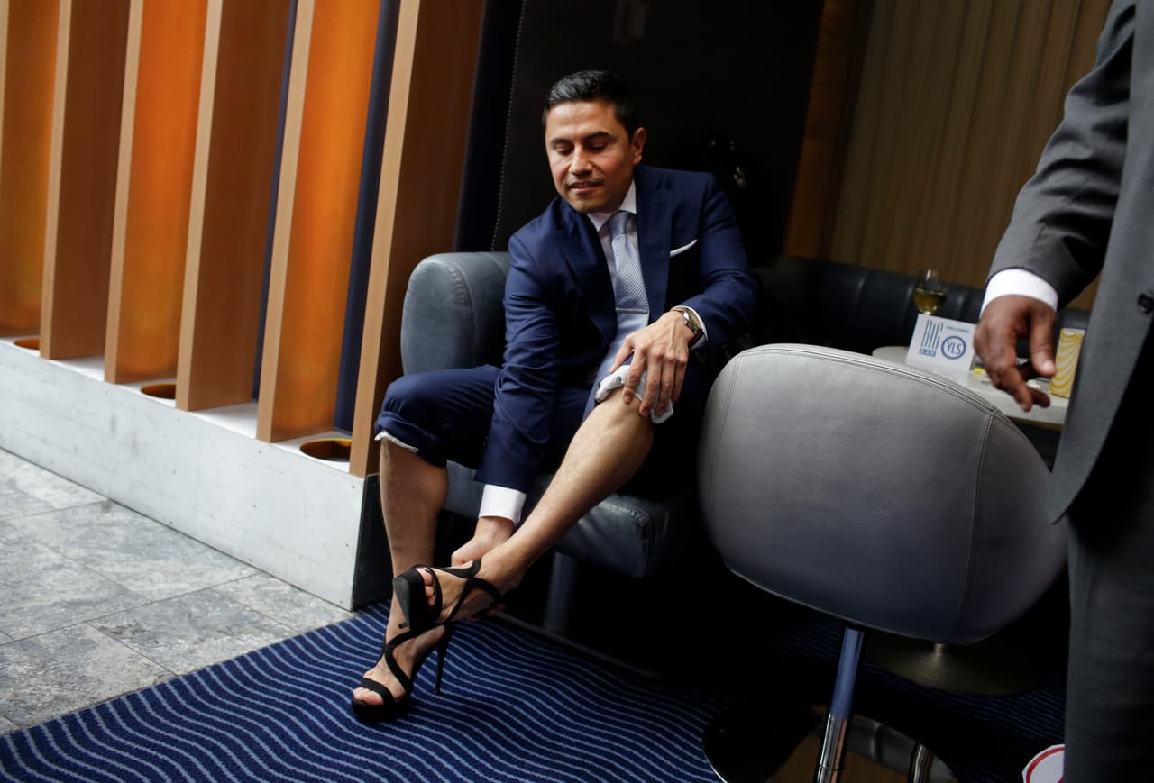 El abogado Octavio Durán se quita los zapatos de tacón alto después de caminar un poco más de kilómetro y medio en esta manifestación que busca crear conciencia sobre el asalto sexual contra las mujeres.