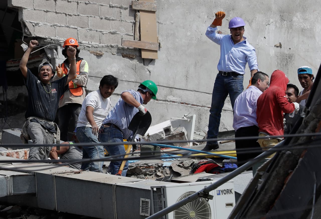 Voluntarios celebran brevemente el rescate de dos personas de un edificio que colapsó en la Colonia Roma, Ciudad de México.