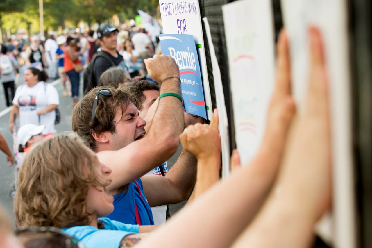 Partidarios de Bernie Sanders en la barda que limita el parque FDR con la arena de la convención.