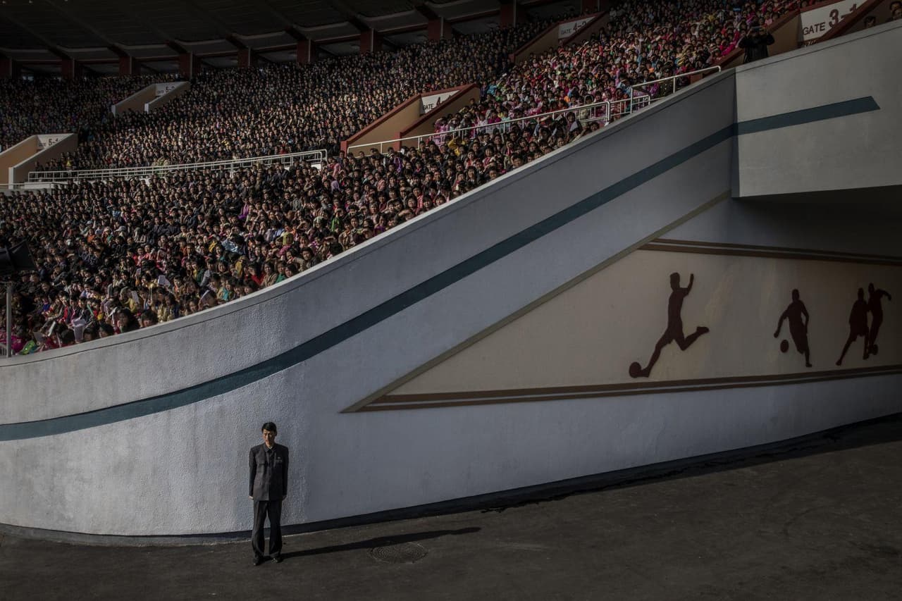 <b>En la puerta del estadio.</b> Esta imagen del fotógrafo Roger Turesson para el diario sueco 
<i>Dagens Nyheter</i> fue tomada en Corea del Norte el 9 de aril de 2017. Muestra a la multitud que aguarda el inicio del maratón de Pyongyang en el estadio Kim Il-sung de esa ciudad, mientras un oficial vigila la salida.