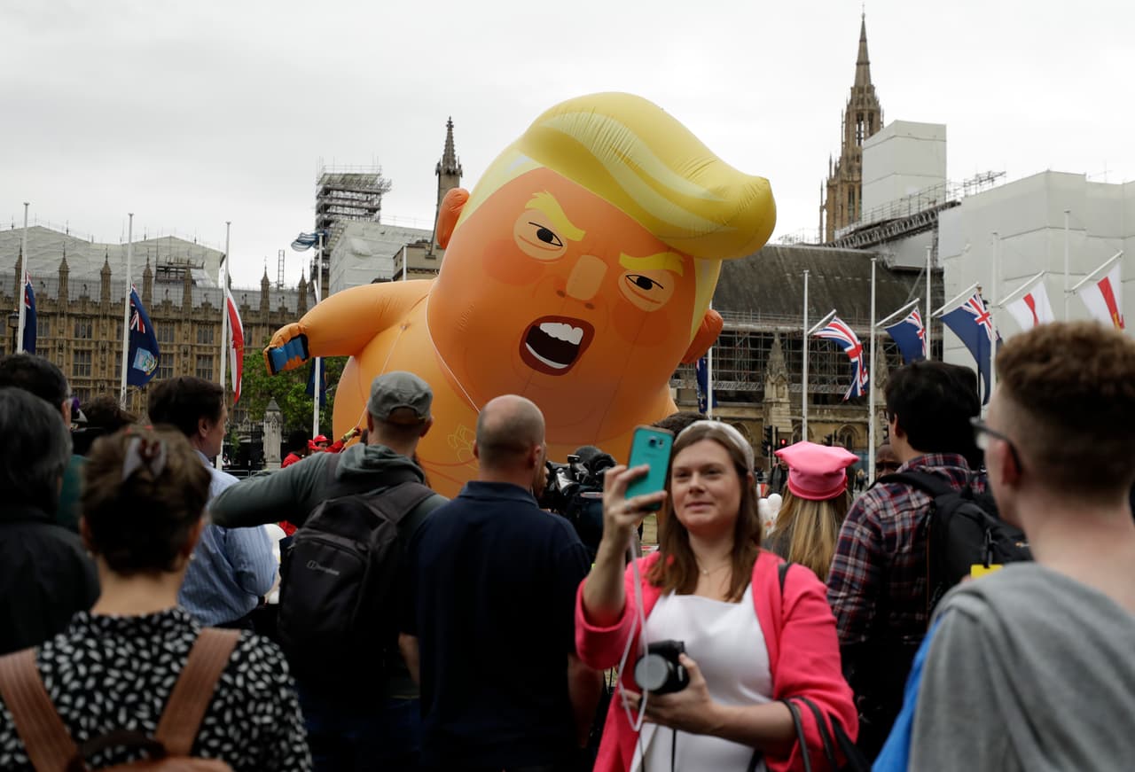 Esta mujer se toma un selfie mientras en el fondo se ve el globo de 'Bebé Trump' que los organizadores de la protesta han llevado al frente del parlamento, en el centro de Londres.
