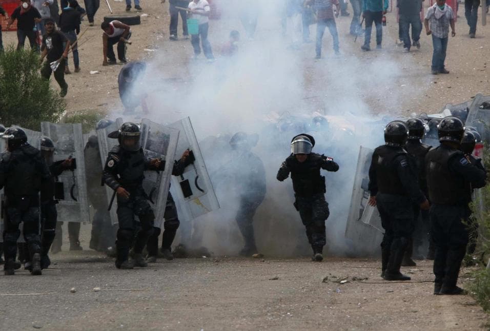 Teachers and police officers amidst a cloud of tear gas