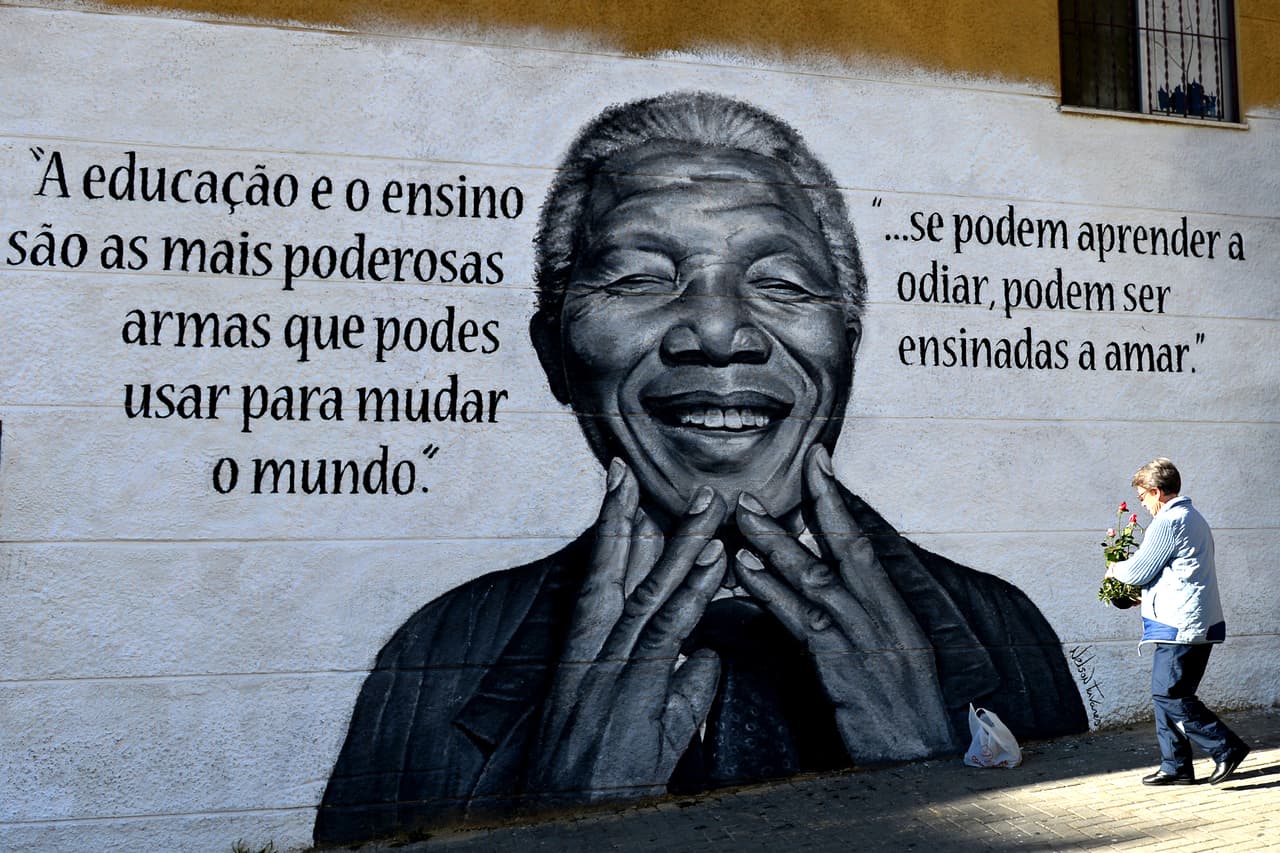Una mujer coloca flores frente a un mural con la imagen del presidente surafricano Nelson Mandela, en Lisboa, Portugal.