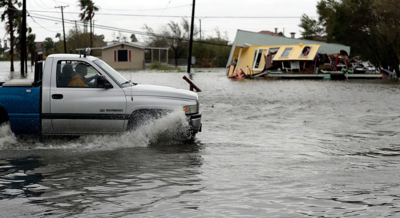 Un camión transita una calle inundada frente a una casa destruida por Harvey, en Aransas Pass, Texas.