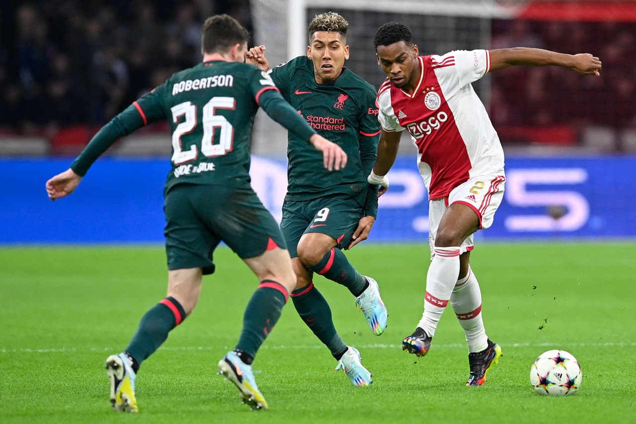 Ajax's Dutch defender Jurrien Timber (R) fights for the ball with Liverpool's Brazilian striker Roberto Firmino (C) and Liverpool's Scottish defender Andrew Robertson (L) during the UEFA Champions League group A football match between Ajax Amsterdam and Liverpool at the Johan Cruijff ArenA in Amsterdam, on October 26, 2022. (Photo by JOHN THYS / AFP) (Photo by JOHN THYS/AFP via Getty Images)