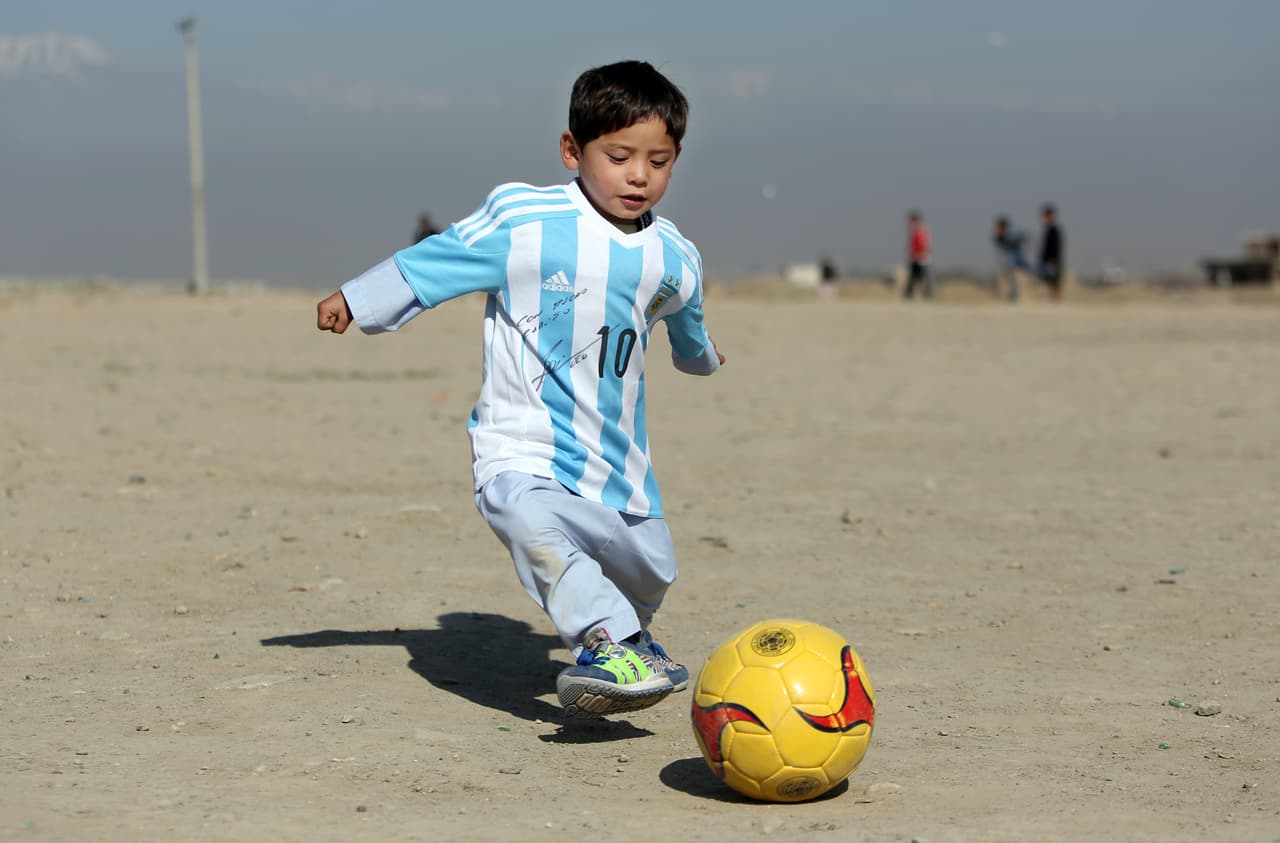 Murtaza Ahmadi, a five-year-old Afghan Lionel Messi fan plays with a soccer ball during a photo opportunity as he wears a shirt signed by Messi, in Kabul, Afghanistan, Friday, Feb. 26, 2016. Mohammad Arif Ahmadi, the father of the boy who was pictured wearing a homemade Argentina shirt with No. 10 on the back, said Friday they want to thank Messi, a UNICEF goodwill ambassador, in person.(AP Photo/Rahmat Gul)