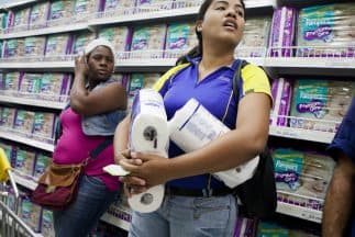 Una mujer recibe cantidad racionada de papel hiegiénico en un automercado administrado por el gobierno venezolano.