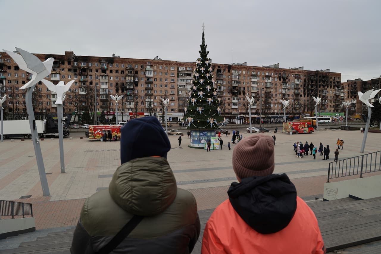Local citizens walk near a Christmas tree decorated for Orthodox Christmas and the New Year festivities in Mariupol, in Russian-controlled Donetsk region, eastern Ukraine, Thursday, Jan. 5, 2023. (AP Photo/Alexei Alexandrov)