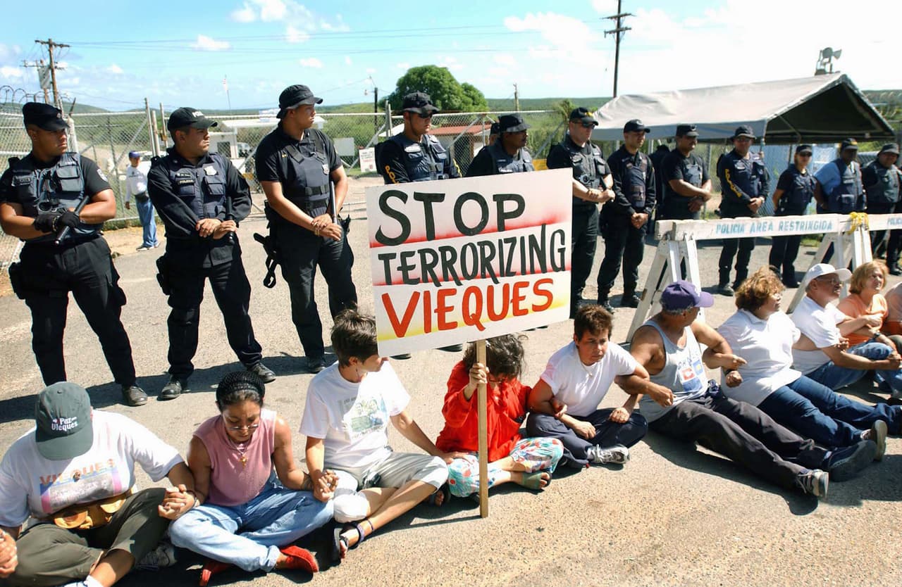 VIEQUES, PUERTO RICO - JANUARY 13: Demonstators block the entrance to Camp Garcia Naval Base January 13, 2003 in Vieques, Puerto Rico. U.S. fighter jets roared over the island on bomber training runs today in what the U.S. Navy has announced will be its last round of nearly six decades of exercises. (Photo by Humberto Trias/Getty Images)