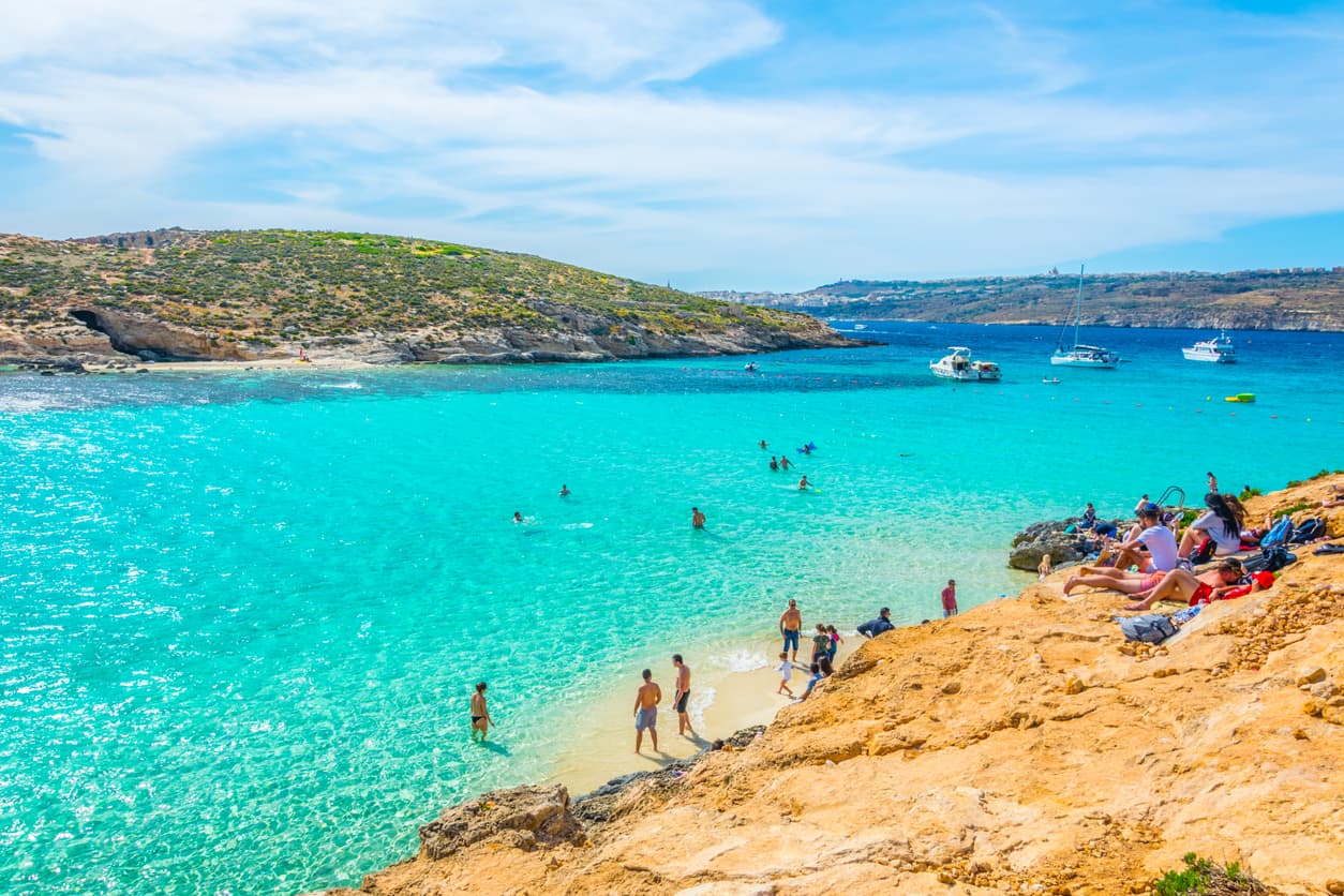 <b>Tiene una población permanente de dos residentes. </b>Antes eran cuatro personas las que vivían en la isla, 
<b>pero dos de ellas fallecieron. </b>El último, informaron medios malteses, murió en diciembre de 2020: su nombre era Anglu Vella y tras fallecer dejó a sus dos parientes, Salvu y Veggie, como los únicos habitantes. 
<br>
<br>En la imagen, turistas visitando la isla de Comino. 
<b>En verano esta isla de playas de arena blanca y ensenadas turquesa recibe decenas de barcos a diario, llenas de turistas que van a pasar el día. </b>