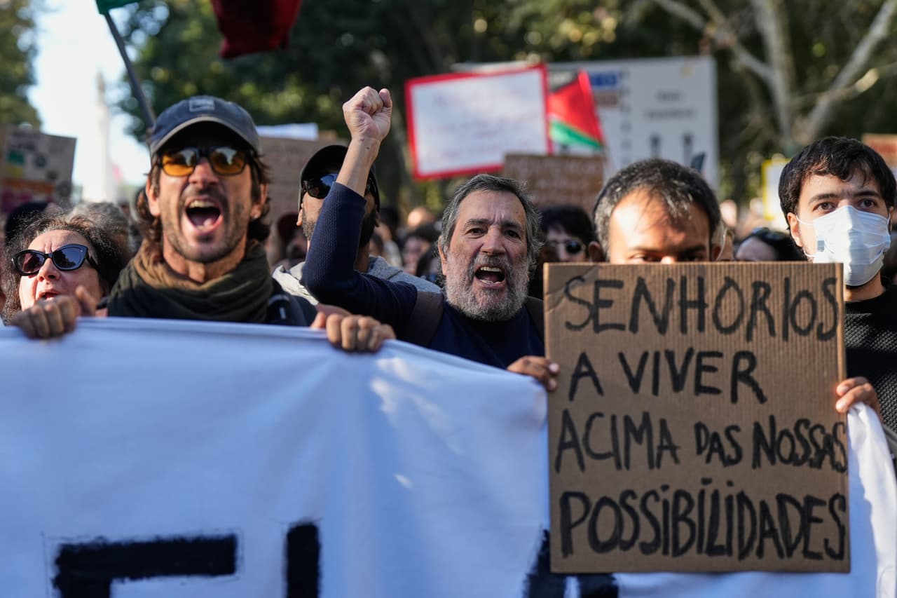 Varias personas sostienen una pancarta con el mensaje en portugués: "Los propietarios viven por encima de nuestras posibilidades"