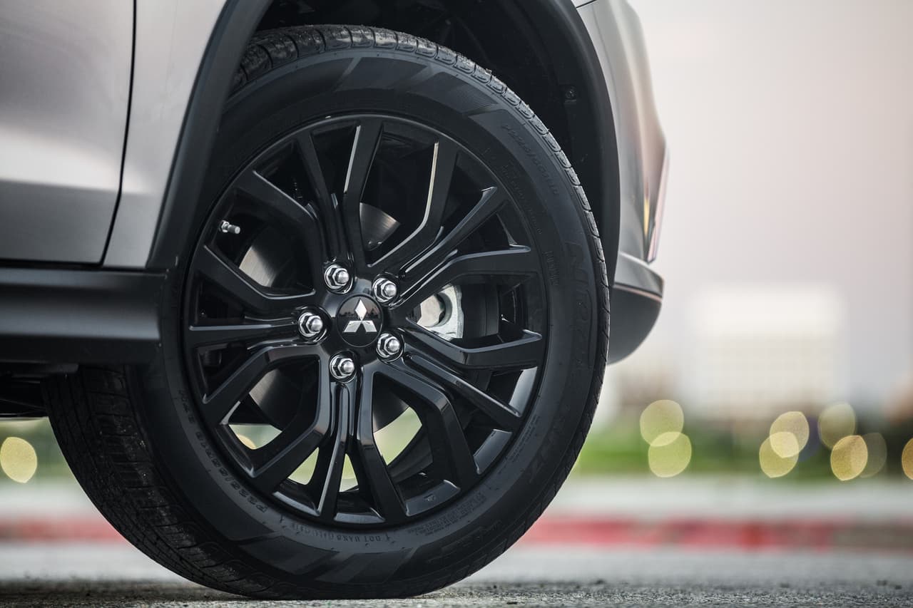 En cuanto a sus rines, son de aleación, de 18 pulgadas, y en color negro. Se puede apreciar el pequeño emblema de Mitsubishi en el centro.