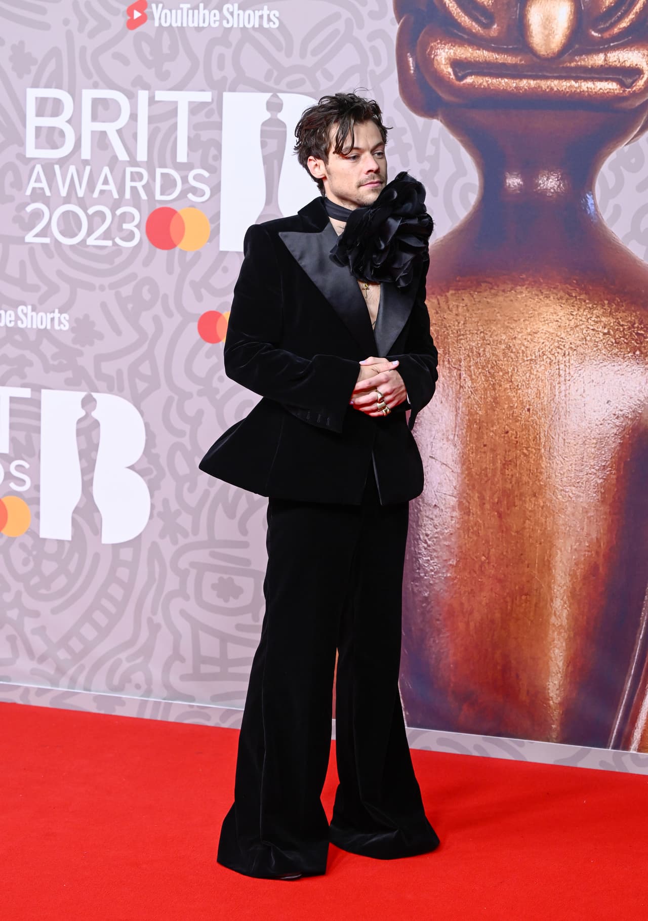 <b>Harry Styles</b> portó un un traje acampanado de terciopelo negro sin camisa que adornó con una enorme flor en el cuello.