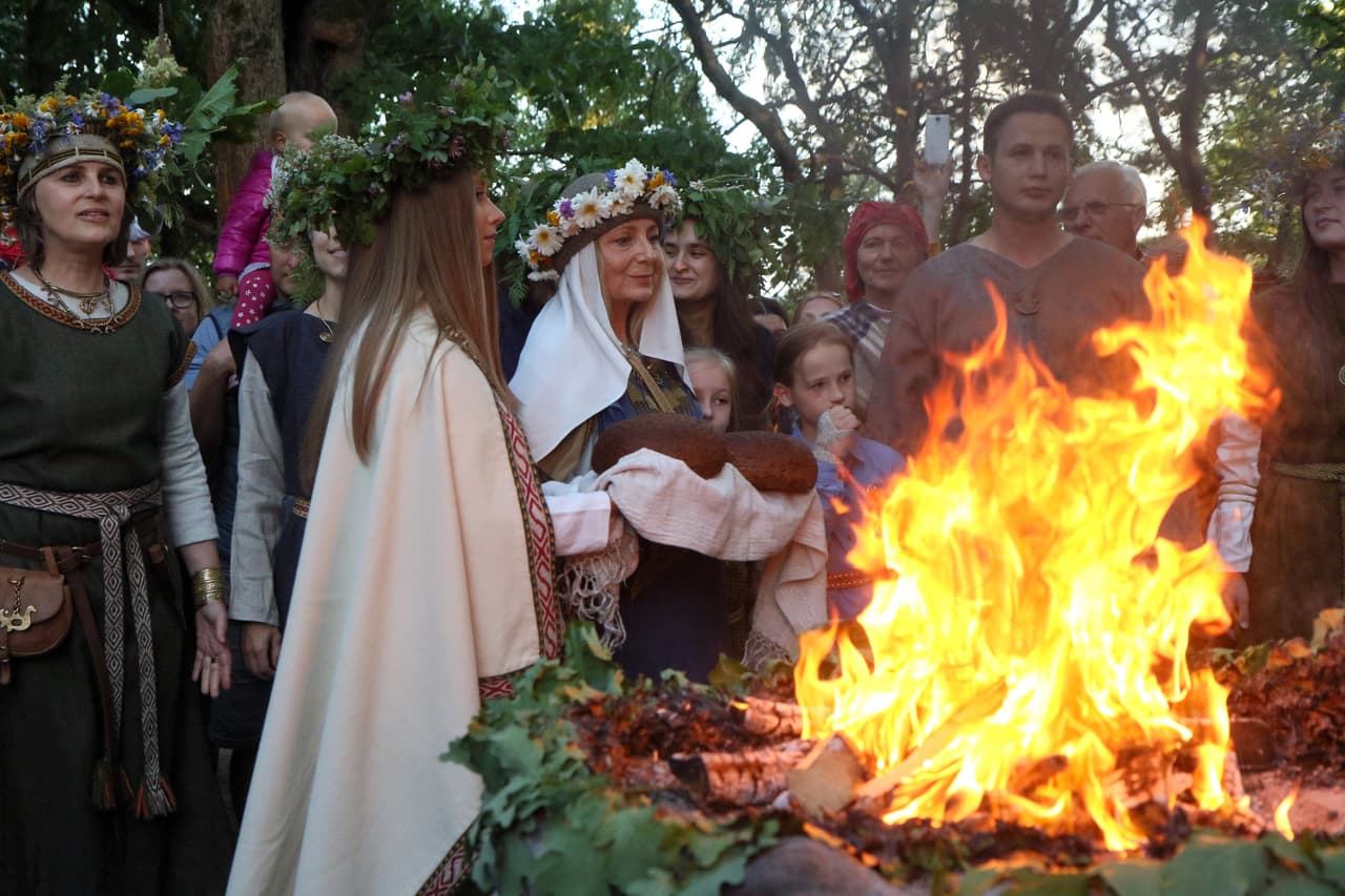 En Lituania, al este de Europa, decenas de miles celebran solsticio de verano alrededor del fuego con coronas de flores en sus cabezas. En la foto la festividad de 2018 frente a un altar de Lizdeika, un sacerdote pagano con atributos de mago que es parte del folclore lituano. 
<br>