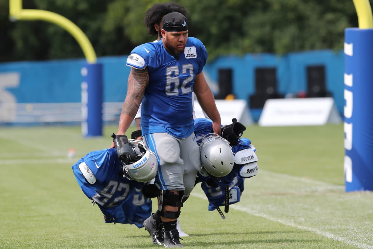 El tacle defensivo novato de los Detroit Lions Josh Fatu transporta el equipamiento de sus compañeros en la práctica del día de su equipo. 'Pagando el precio' de ser novato.