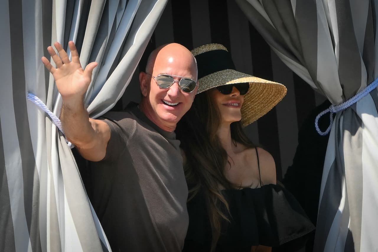 Bezos y su esposa Sánchez Bezos saludan al llegar al Hotel Aman tras un almuerzo.
<br>
<br>Pero el perfil de Bezos genera más divisiones por su inmensa fortuna y por las críticas por el trato que Amazon da a sus trabajadores o el impacto medioambiental de su empresa aeroespacial, Blue Origin.
<br>