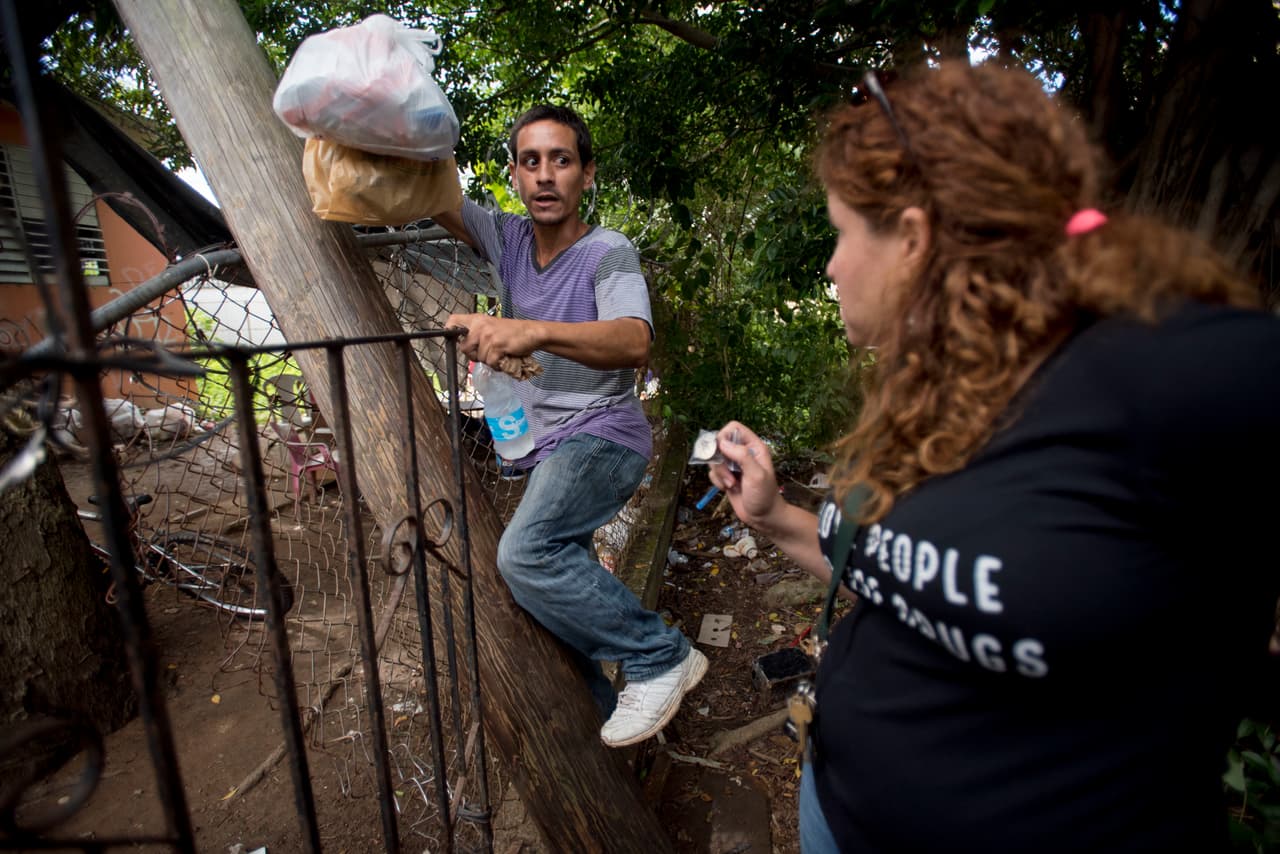 Alexandra Bárcenas, voluntaria del programa "Intercambios Puerto Rico", habla con un adicto a la heroína, Jimmy Berríos Medina, que se dirige a la parte trasera de una casa abandonada popular entre los adictos en Humacao.