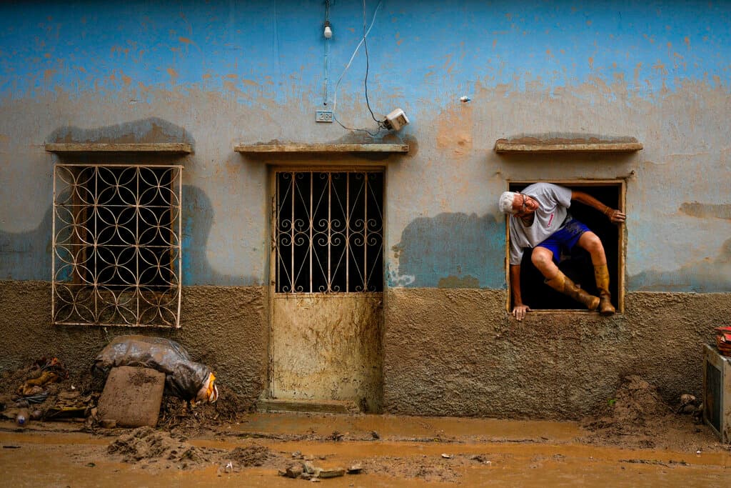 Jose Medina salta por una ventana de su casa afectada por el desplazamiento de lodo, tierra y escombros en Las Tejerías, Venezuela.