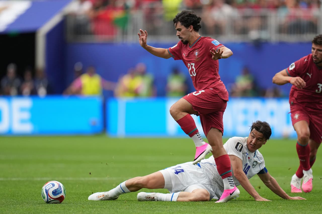 Eldor Shomurodov (14), de Uzbekistán, abajo, intenta detener a Vitinha (23), de Portugal, durante el partido de fútbol del Grupo K de la Copa Mundial entre Portugal y Uzbekistán