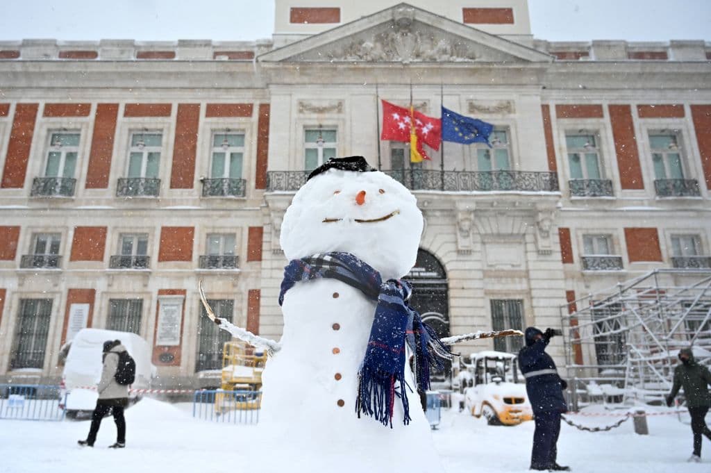 La gente pasa junto a un muñeco de nieve en la icónica Puerta del Sol, considerada el centro del país, en medio de una fuerte nevada el 9 de enero de 2021.