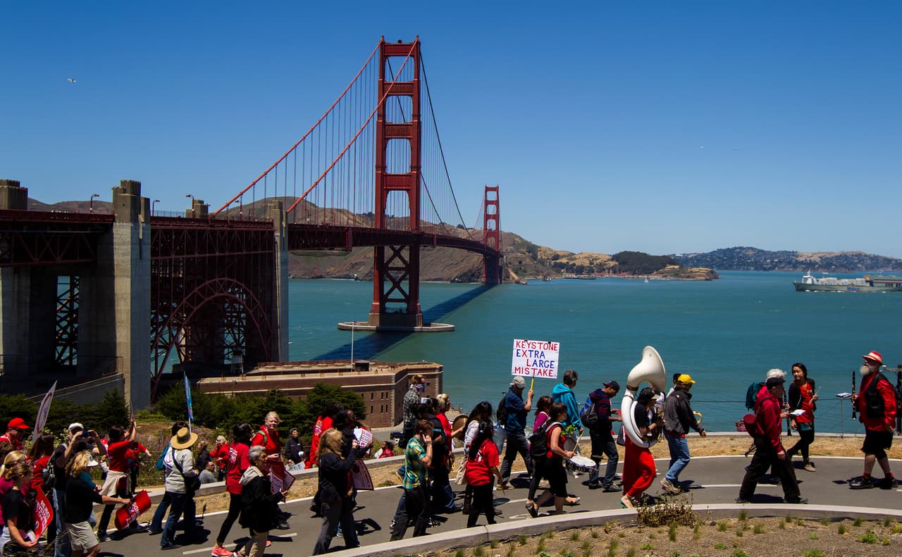 <b>Las medidas. </b>La longitud total del puente es de 6,463 pies. De norte a sur y de sur a norte hay 1131 pies desde las bases hasta las torres y 4,200 pies de estructura totalmente colgante. Del lado sur, saliendo de San Francisco, un pequeño puente de arco es el inicio del recorrido total del Golden Gate. La fotografía fue tomada en una protesta de enfermeras y activistas ambientales en 2013.