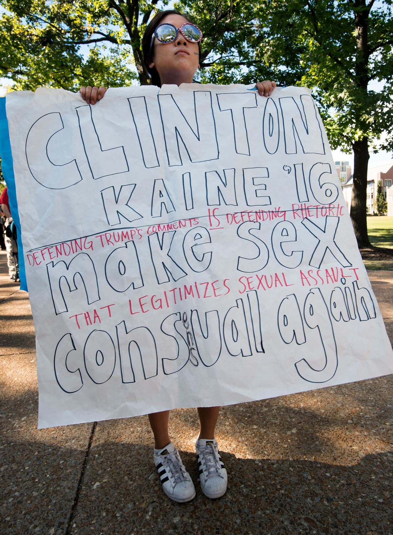 Seohyun Kim, estudiante de la universidad Washington muestra un cartel en contra de Donald Trump a los medios.