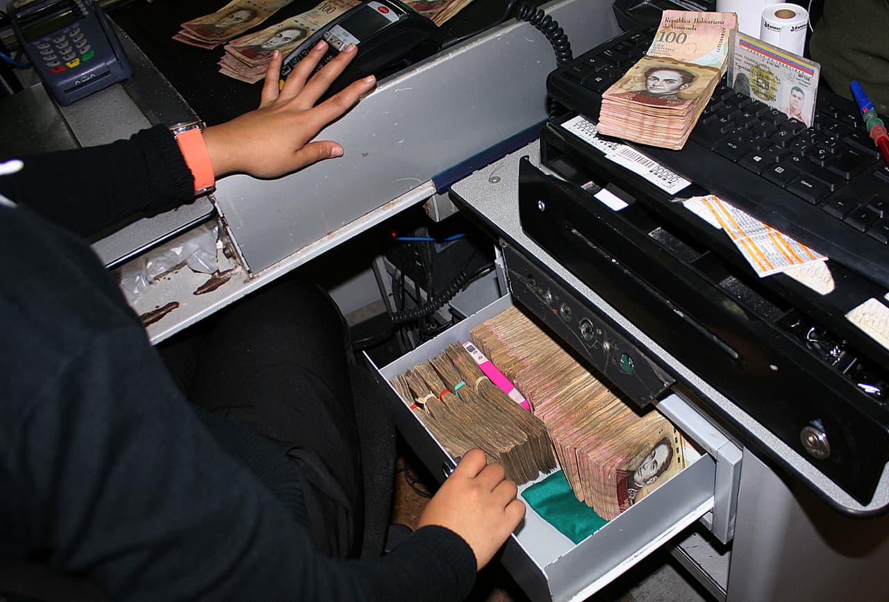 El día siguiente al anuncio de Maduro fue feriado bancario y los venezolanos no pudieron acudir a las taquillas a depositar altas sumas de dinero.En el estado fronterizo de Táchira, una mujer almacena pacas de billetes de 100 bolívares en la caja registradora.