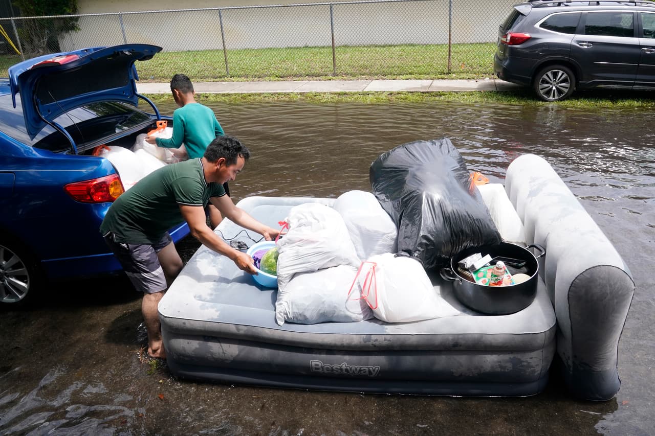 Adrián Vásquez y su hijo llevan artículos de su casa inundada a su automóvil el jueves 13 de abril de 2023 en Fort Lauderdale, Florida. La casa de Vásquez sufrió graves daños después de que se inundara por la lluvia, destruyendo la mayoría de las pertenencias de su familia. Fort Lauderdale emitió un estado de emergencia debido a que las inundaciones persistieron en partes de la ciudad.