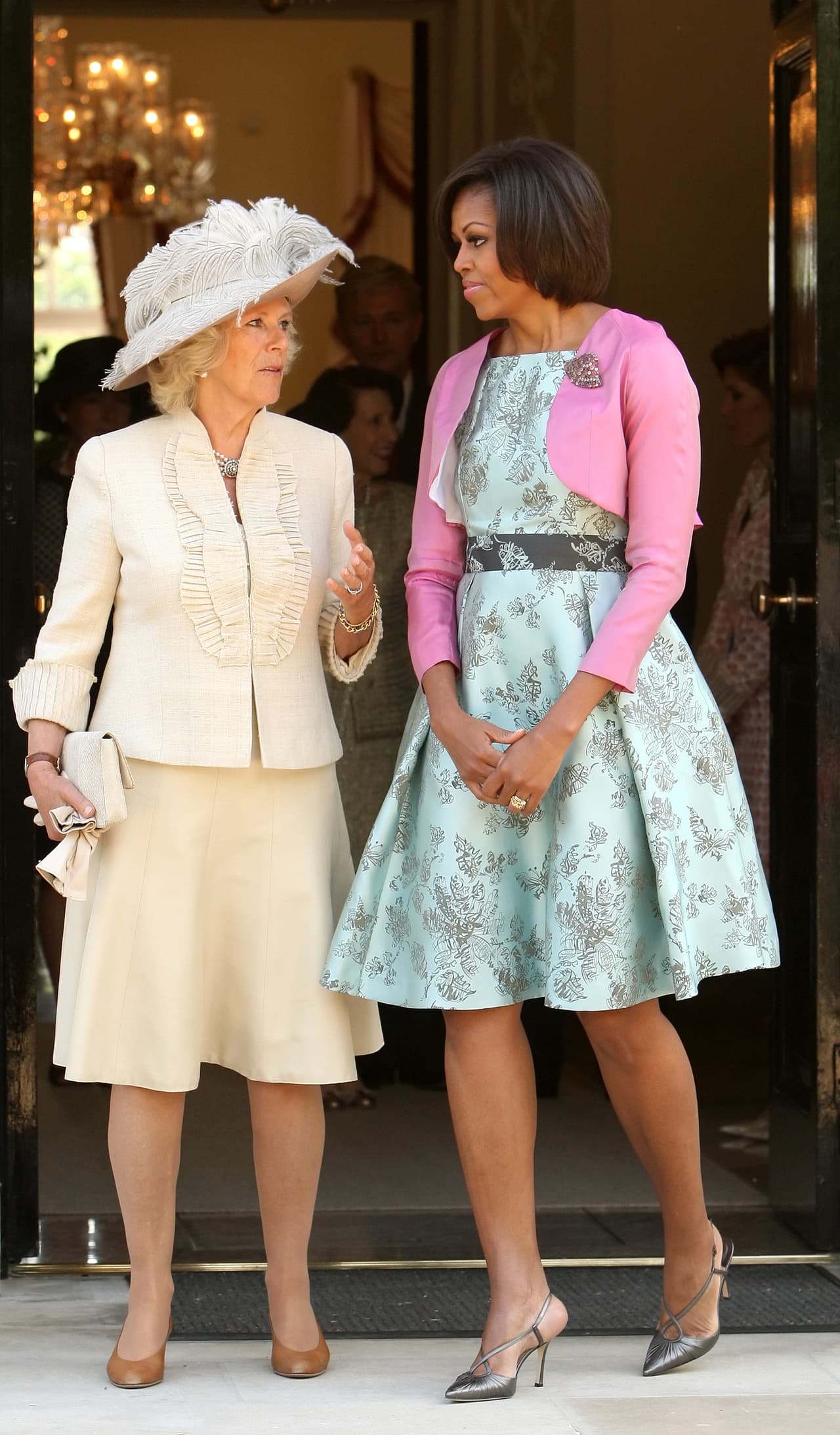 Para asistir al Palacio de Buckingham, qué mejor que retomar esos vibrantes colores a los que la Reina Isabel nos tiene acostumbrados y elegir un vestido de corte 'lady like' en tono azul aguamarina y rosado diseñado por Barbara Tfank.