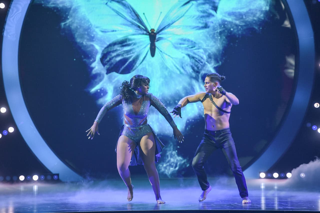 Segunda gala: Desde lo alto,
<a href="https://www.univision.com/shows/mira-quien-baila/como-una-pluma-amara-la-negra-flota-literalmente-en-los-aires-en-su-adagio-fotos" target="_blank">Amara 'La Negra' descendió para bailar al ritmo de la canción 'Me muero'</a> de la serie 'Amar a muerte', contó con Carlos Rivera como invitado.