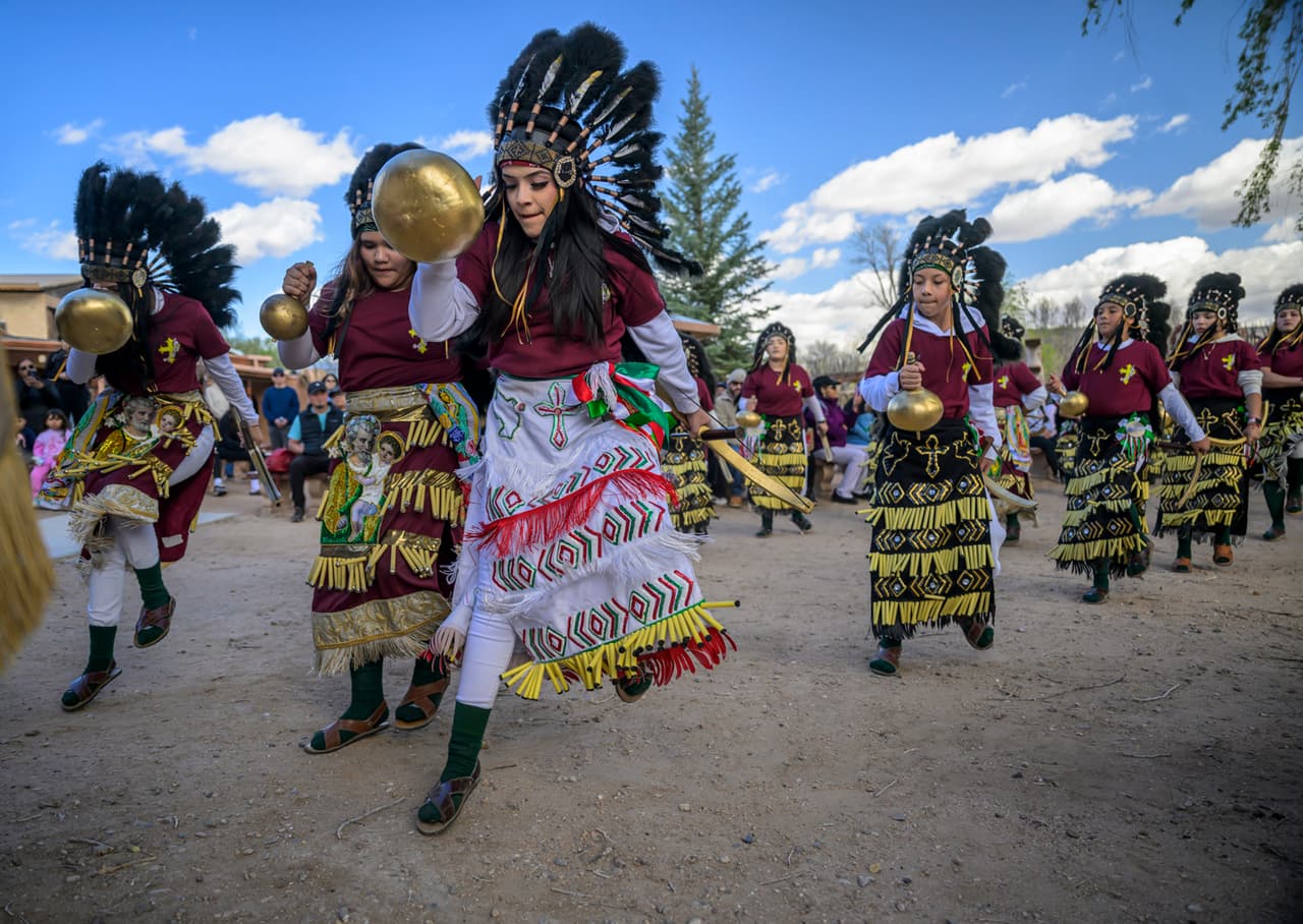 Miembros del grupo de danza Danza Señor San José se presentan detrás del Santuario de Chimayó en el norte de Nuevo México durante la Semana Santa, el Viernes Santo.