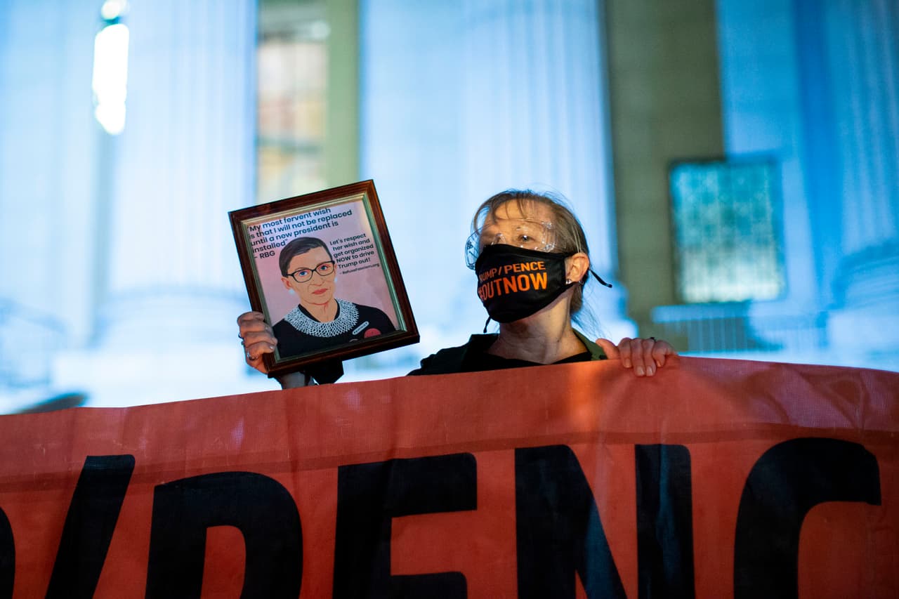 Una mujer sostiene una foto mientras la gente presenta sus respetos a Ruth Bader Ginsburg.