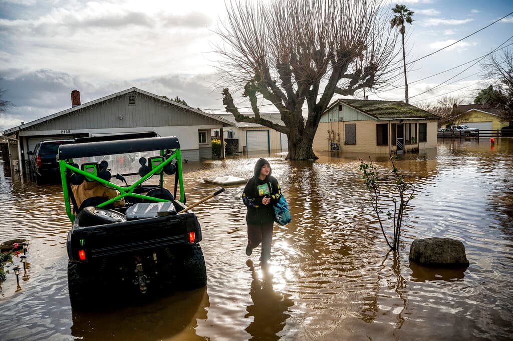 Brenda Ortega, de 15 años, sale de su casa en Merced, debido a la enorme inundación. Los 4,000 residentes de la vecina Planada recibieron la orden de marcharse el martes por la mañana. Los barrios estaban bajo el agua y los autos sumergidos hasta el techo. Los residentes a los que se ordenó evacuar cargaron con lo que pudieron salvar mientras salían bajo la lluvia. Se ordenaron otras evacuaciones debido a la rotura de diques en algunas partes del condado de Monterey.