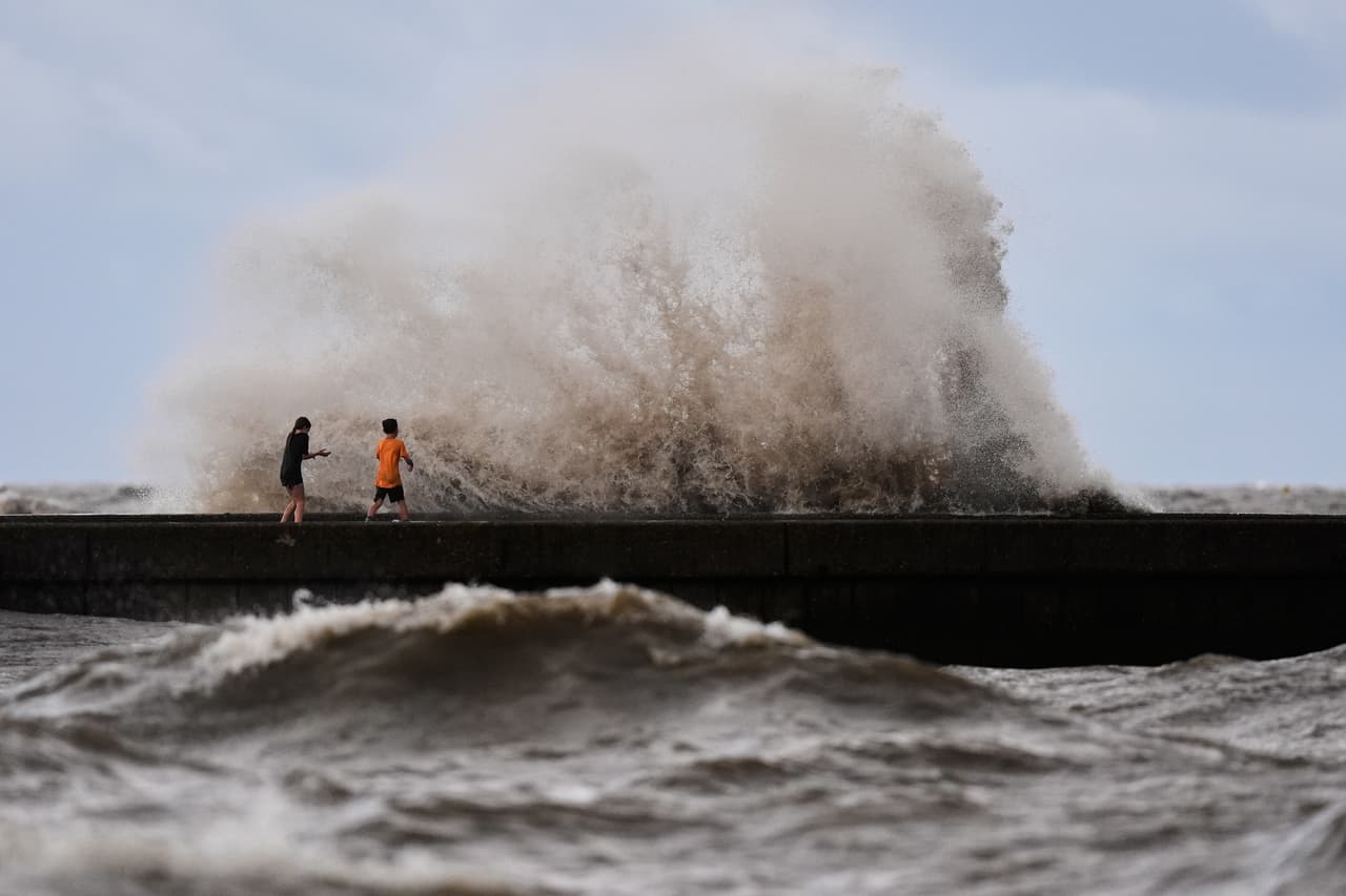 Unos niños juegan cerca de las olas que rompen en el muelle de West End, en el lago Pontchartrain, mientras la tormenta tropical Bertha se acerca a la costa de Luisiana el miércoles 22 de julio de 2026, en Nueva Orleans. (Foto AP/Gerald Herbert)