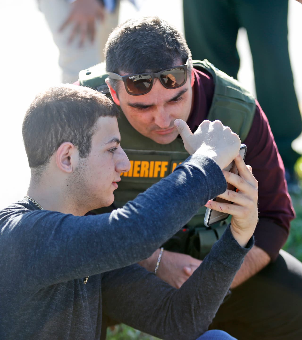 Un alumno de la secundaria Marjory Stoneman Douglas muestra fotografías de su teléfono a un policía.