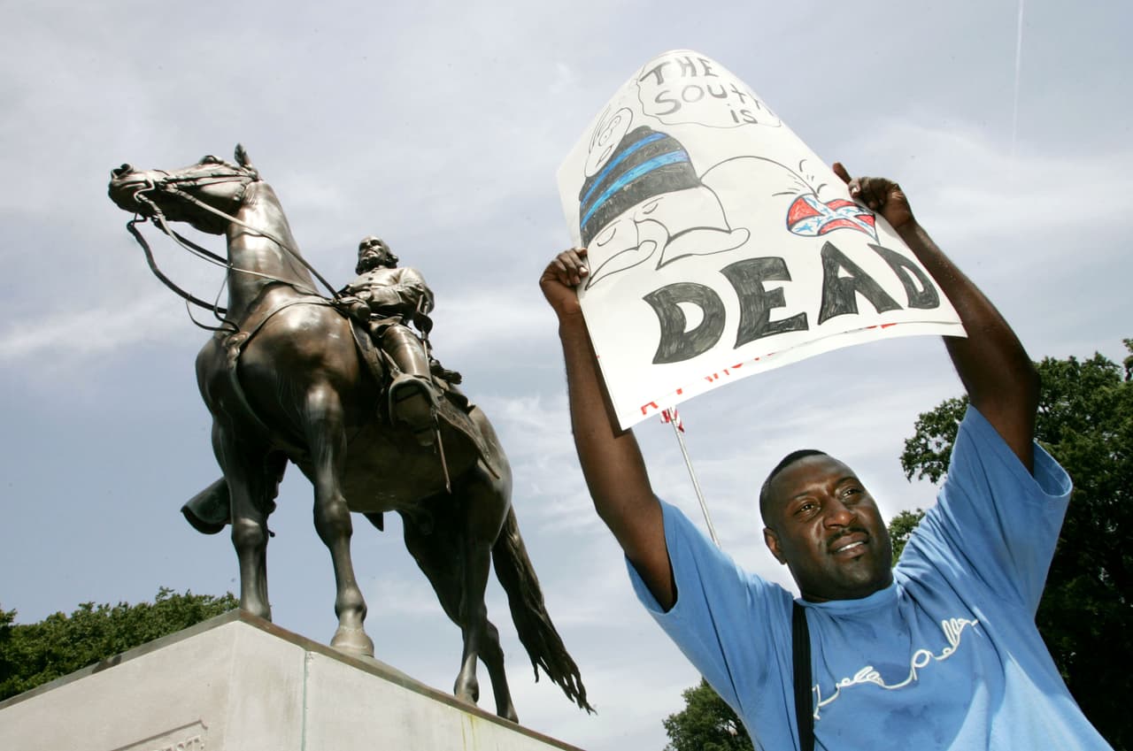 MEMPHIS, TN - AUGUST 13: Protester Maurice Spivey holds up a sign to protest against the name of Nathan Bedford Forrest Park in front of a statue bearing his likeness August 13, 2005 in Memphis, Tennessee. Nathan Bedford Forrest was a Civil War General who led troops against the north. Forrest was originally buried in Elmwood Cemetery in Memphis. In 1905 Confederate veterans arranged to move his remains and those of his wife Mary to a new site, named Forrest Park, which is adorned with a statue of him riding a horse. (Photo by Carlo Allegri/Getty Images)