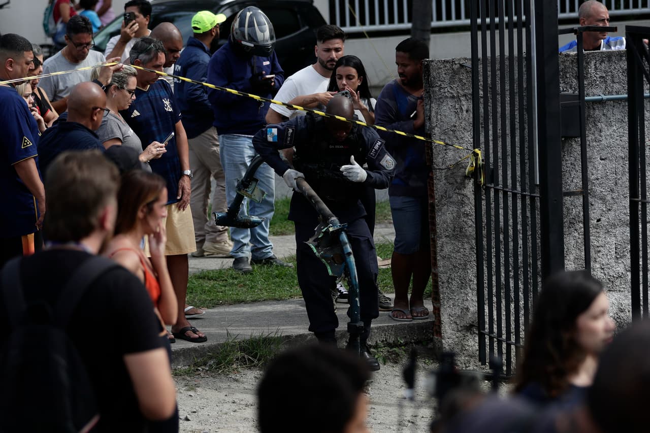 A police officer carries debris at the site where two helicopters reportedly collided in midair and crashed into a car dealership parking lot in Rio de Janeiro, Brazil, Sunday, June 14, 2026. (AP Photo/Bruna Prado)