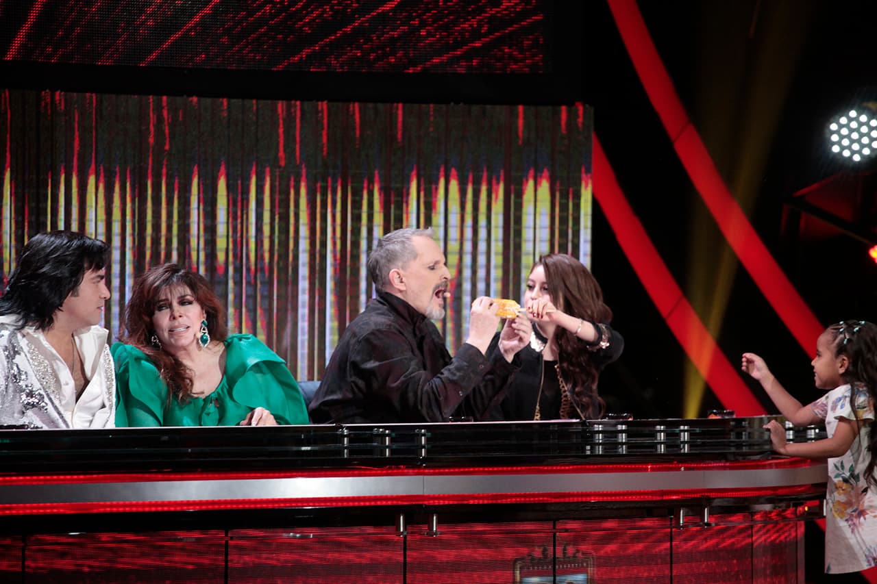 Llena de disposición, Karol llevó el elote hasta la boca del intérprete español.