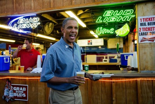 El presidente Barack Obama sostiene un vaso con cerveza y un plato con una chuleta de cerdo en un local de la Feria Estatal de Iowa, en Des Moines, el 13 de agosto de 2012.