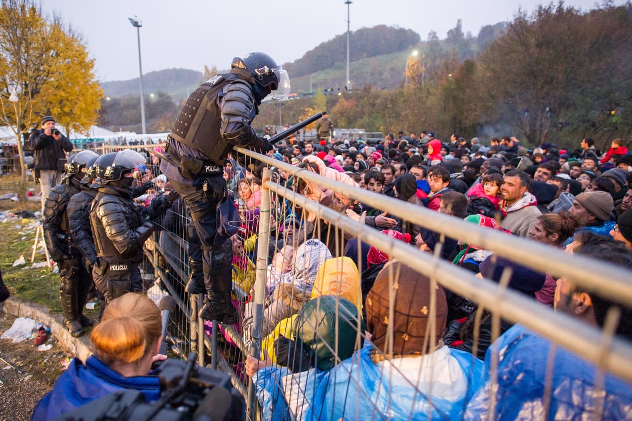 <b>Eslovenia - Austria. </b>Esta es una de las últimas barreras que enfrentan los migrantes en Europa. En la foto, un policía Esloveno se sube a la barda para rescatar a un niño atrapado por la masa de personas que intentan llegar al cruce de la frontera. 29 de octubre de 2015.
<br>