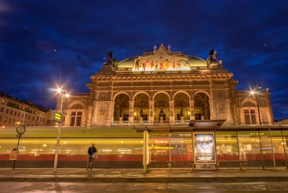 Una mujer espera a un tranvía de la ciudad frente al teatro de Opera Wiener Staatsoper, de Viena.