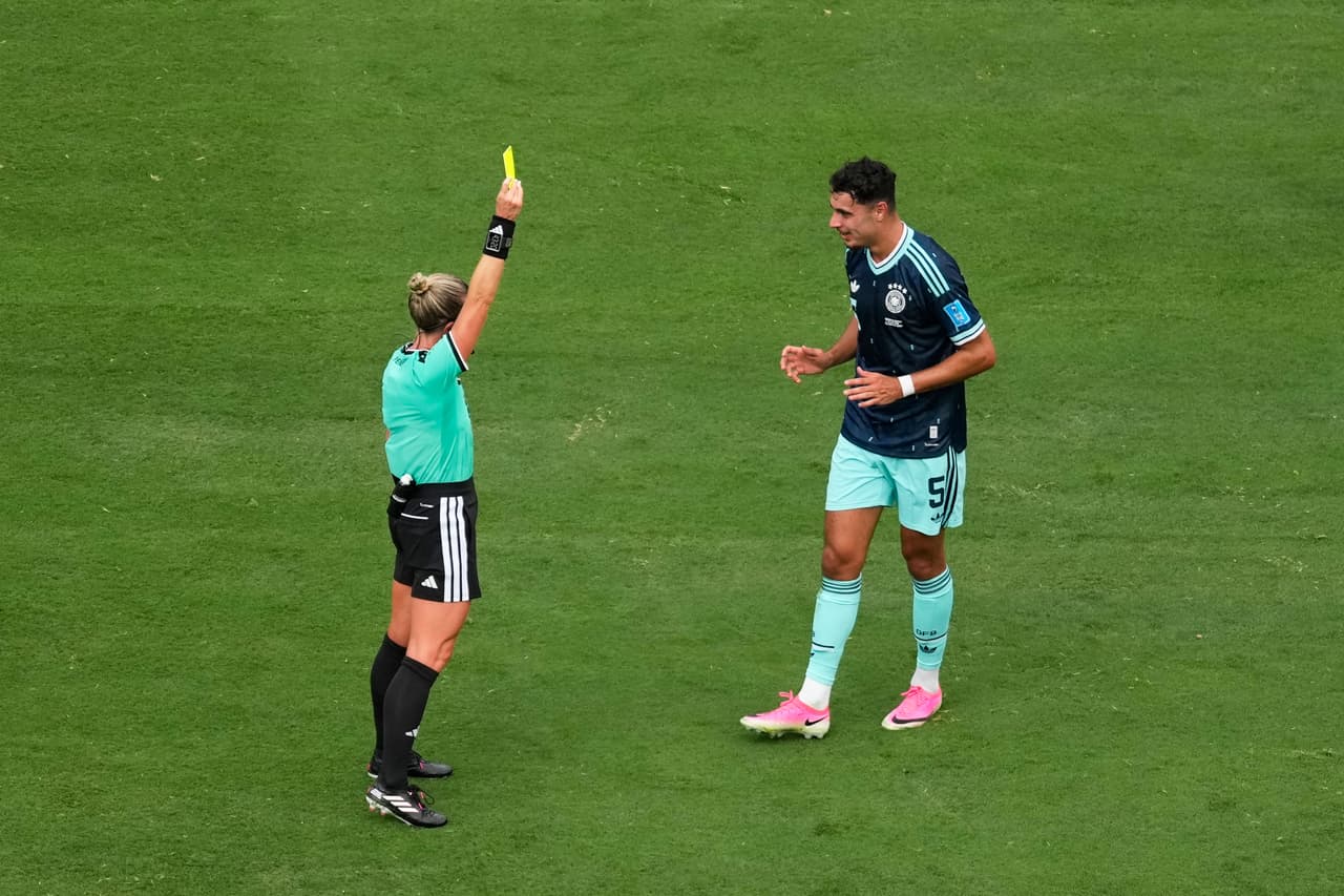 El árbitro le muestra una tarjeta amarilla a Aleksandar Pavlovic de Alemania.