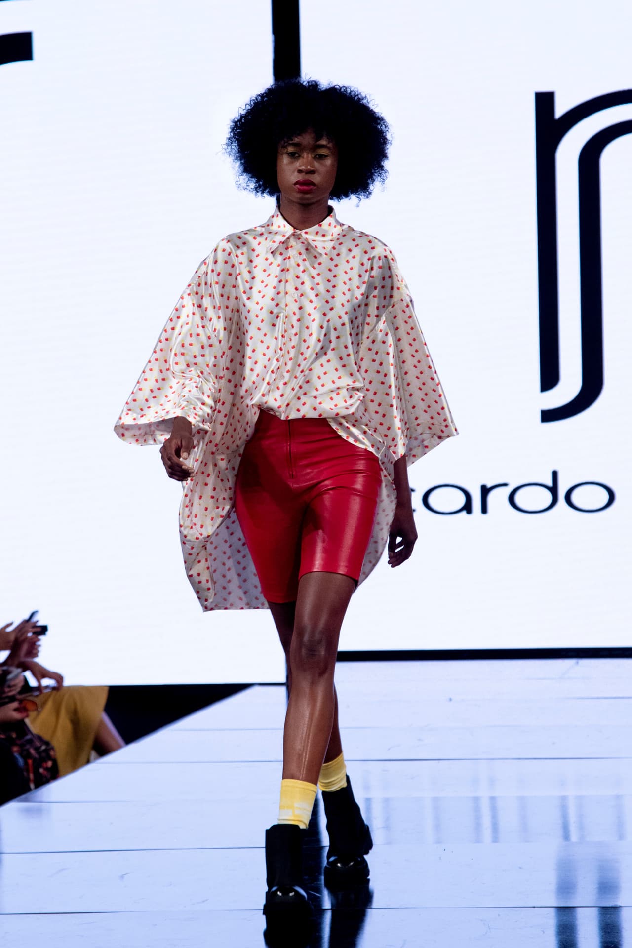 La imagen de El Chapulín Colorado, así como la CH que imperaba en su corazón, protagonizan el estampado con el que 
<b><a href="https://www.ricardoseco.com/" target="_blank">Ricardo Seco</a></b> creó camisas "oversize", como la que se observa en esta foto.