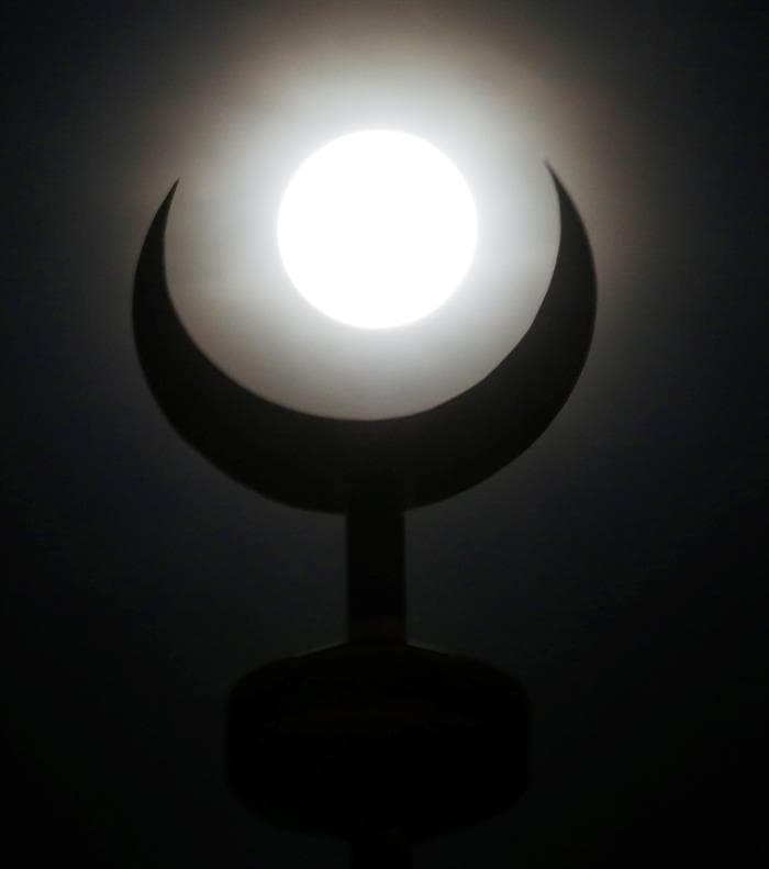 La luna llena brilla tras el símbolo de la media luna creciente en el minarete de una mezquita en Manila (Filipinas).